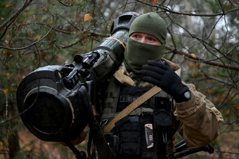 This photo, taken on November 3, 2022, shows a Ukrainian border guard carrying an Anglo-Swedish NLAW anti-tank missile launcher in a fortified position near the Ukrainian border with Russia and Belarus. 