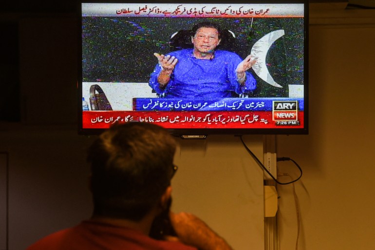 A man watches a television channel broadcasting the address of Pakistani former prime minister Imran Khan