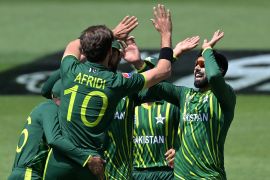 Pakistan players in green uniforms with yellow numbers high-fiving each other