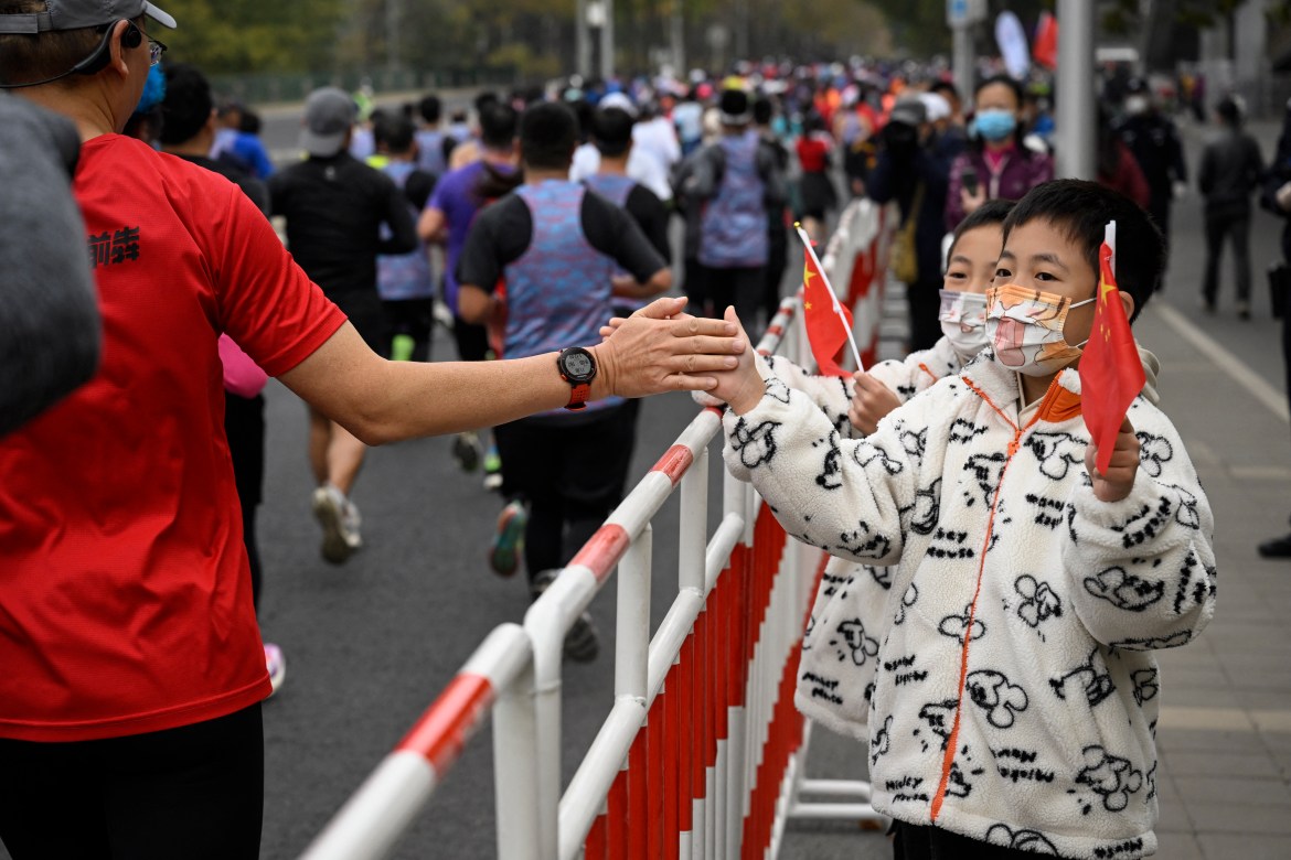 Two children cheer for runners during the Beijing Marathon