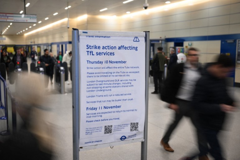 Commuters walk past a sign announcing service disruption at Stratford Station in London