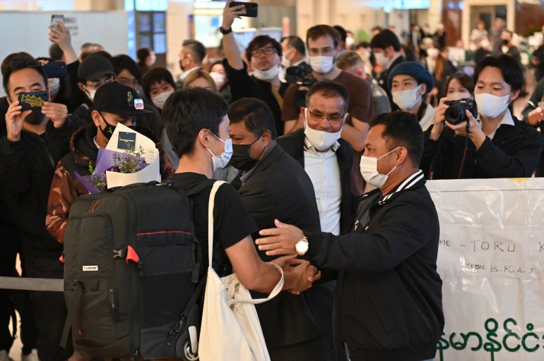 Japanese journalist Toru Kubota holds a black bag as he is greeted by supporters as he looks happy at Haneda Airport in Tokyo 