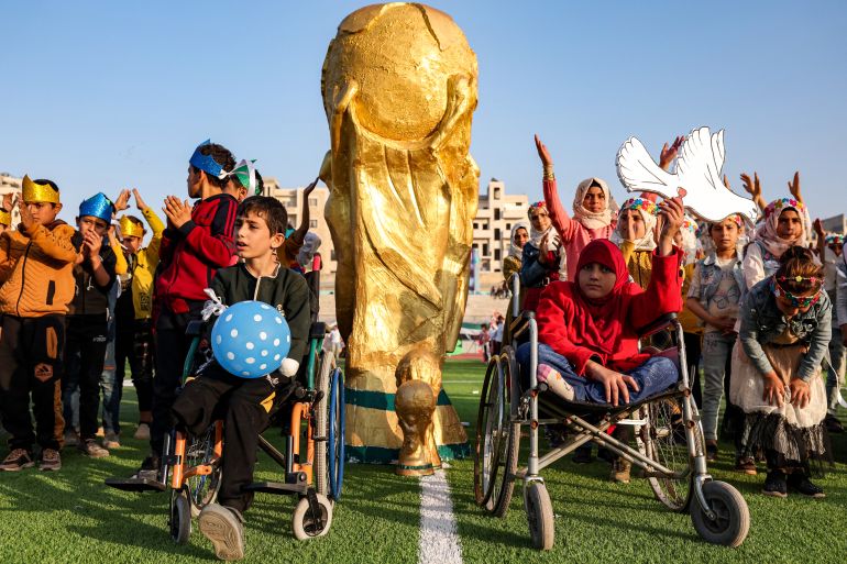 Children pose by a mockup of the FIFA World Cup trophy