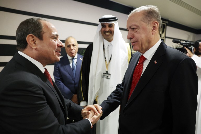This handout photograph taken and released by The Press Office of the Presidency of Turkey on November 20, 2022, shows Turkish President Recep Tayyip Erdogan (R) shakes hands with Egyptian President Abdel Fattah el-Sisi as they are welcomed by Qatari Emir Sheikh Tamim bin Hamad al-Thani (2ndR) on the occasion of the opening ceremony of the 2022 FIFA World Cup in Doha, Qatar. (Photo by Handout / Press Office of the Presidency of Turkey / AFP) / RESTRICTED TO EDITORIAL USE - MANDATORY CREDIT "AFP PHOTO / HO - PRESS OFFICE OF THE PRESIDENCY OF TURKEY" - NO MARKETING NO ADVERTISING CAMPAIGNS - DISTRIBUTED AS A SERVICE TO CLIENTS
