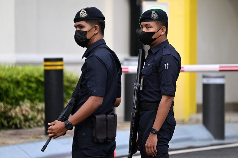 Two armed Malaysian police officers outside the palace in Kuala Lumpur
