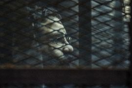 Egyptian activist Alaa Abdel Fattah stands behind bars with fellow defendants during their verdict at a police institute in Cairo's Tora prison on February 23, 2015.