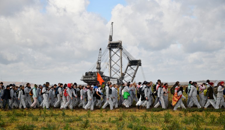 Environmentalists march past a giant bucket-wheel excavator of the Hambach lignite open pit mine near Elsdorf, western Germany, on November 5, 2017, during a protest against fossil-based energies like coal.