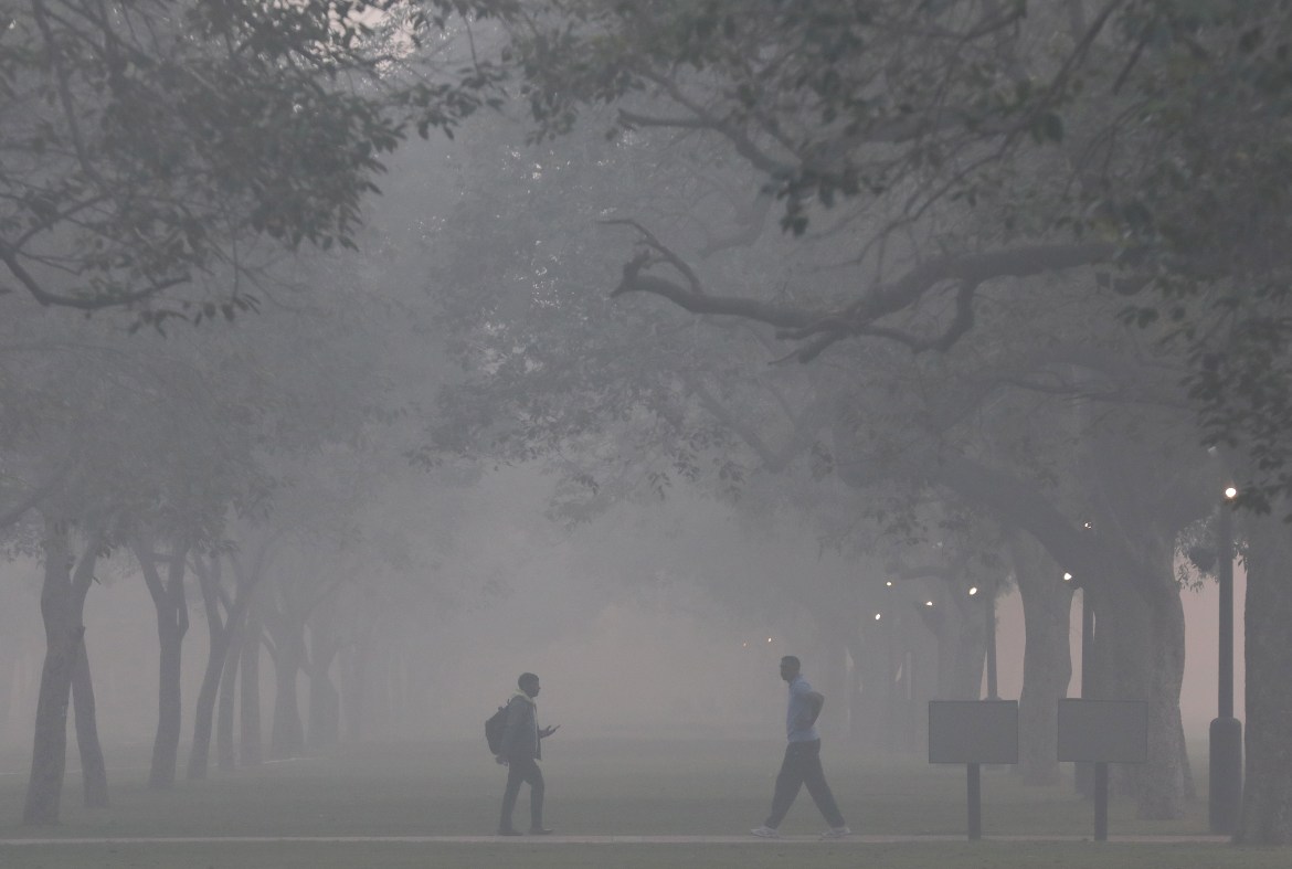 People walk as the city is engulfed in heavy smog near Rajpath, in New Delhi