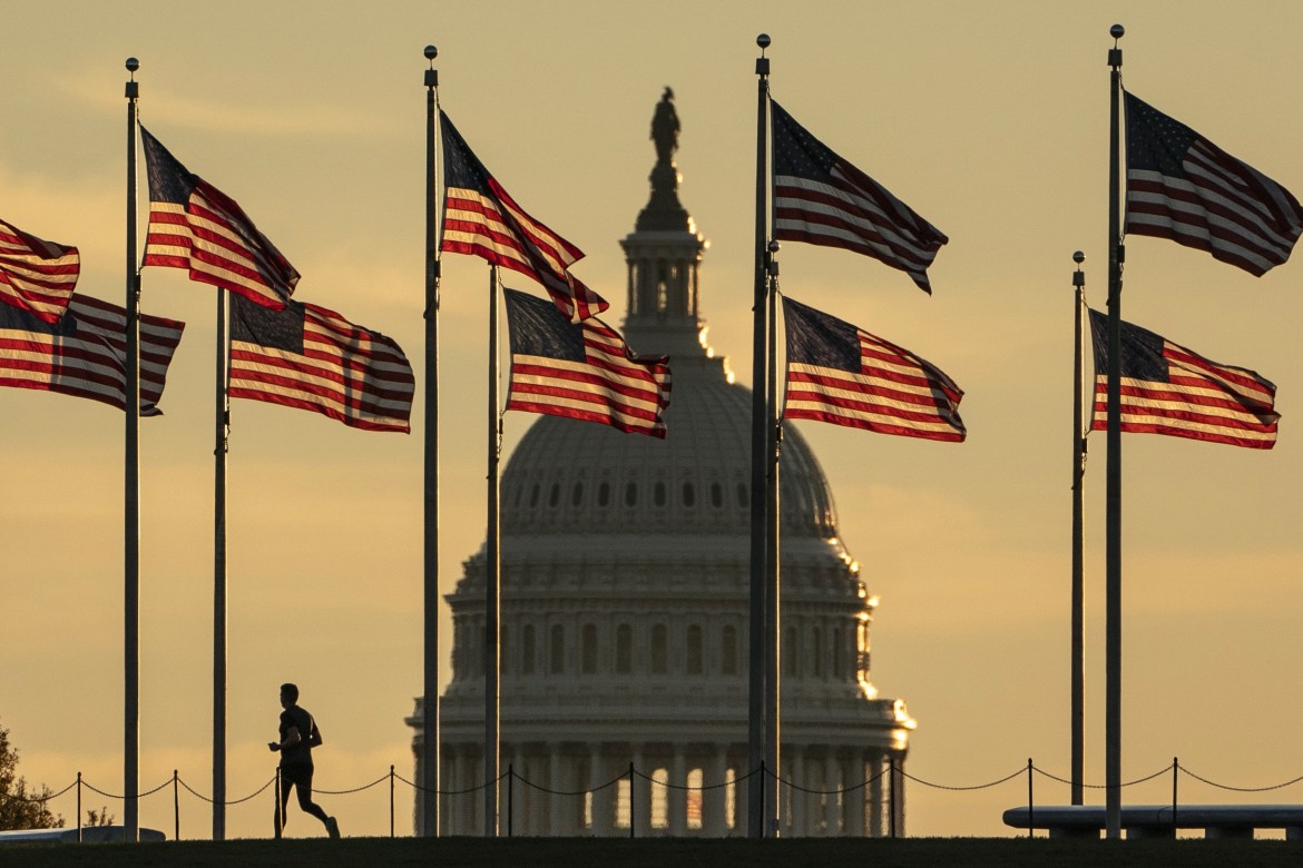 A jogger passes US flags on the National Mall in front of the Capitol Building in Washington, DC.
