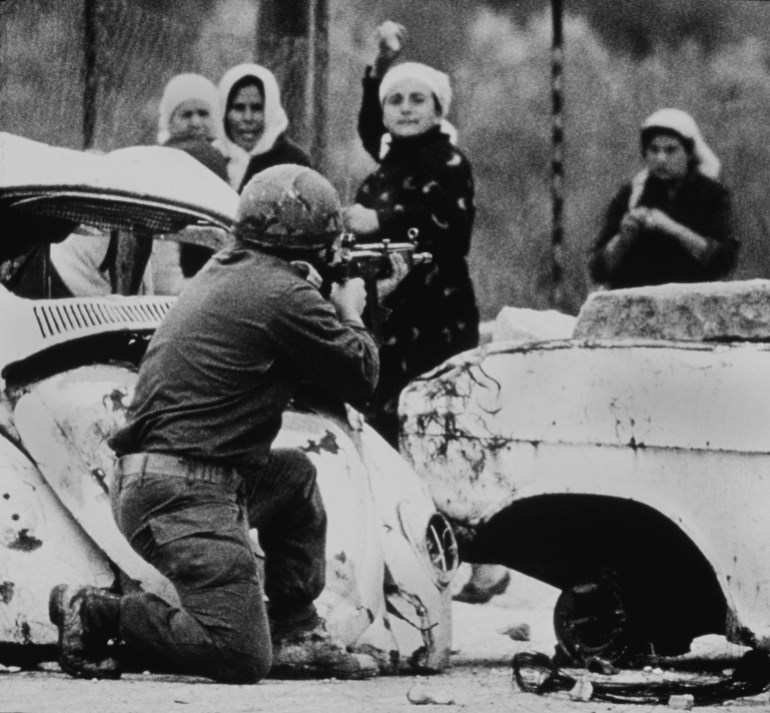 DOSSIER PHOTO 29 FÉVRIER 1988 - Un soldat israélien vise alors qu'une Palestinienne lui lance une pierre à bout portant lors d'une manifestation au cours de laquelle un jeune Palestinien a été abattu plusieurs mois après le déclenchement de la guerre "Intifada", ou le soulèvement palestinien contre l'occupation israélienne.  Les Palestiniens célèbrent le 10e anniversaire de l'intifada qui a commencé soudainement le 9 décembre 1987 dans la bande de Gaza et s'est rapidement étendue à la Cisjordanie.  L'Intifada a engendré les accords de paix israélo-palestiniens, qui ont commencé en 1992 après la conférence de paix historique de Madrid, mais de nombreux Palestiniens se sentent abandonnés une décennie plus tard par l'absence de résultats.