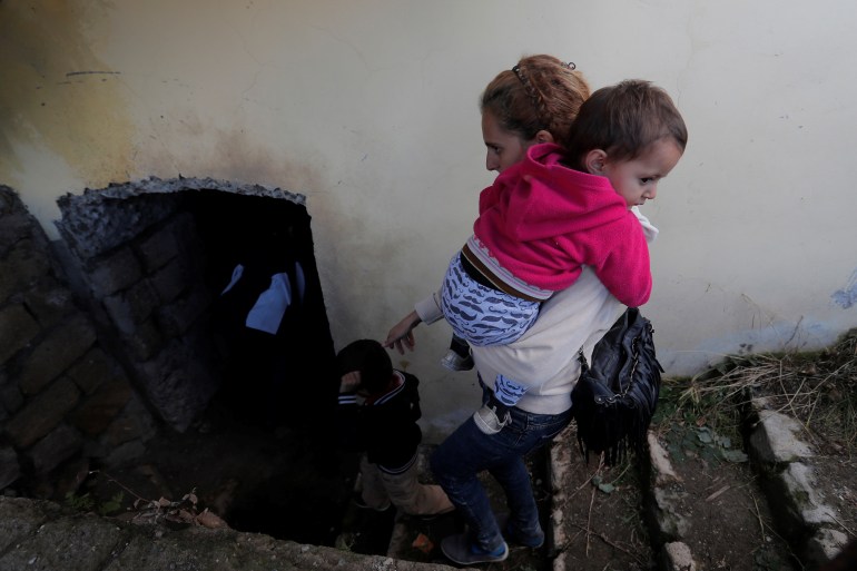 A woman and children go down to the basement of a building to take shelter during the fighting over the breakaway region of Nagorno-Karabakh, in Shushi (Shusha) October 8, 2020. REUTERS/Stringer