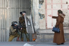 A Palestinian woman gestures in front of Israeli troops during a protest over the killing of three Palestinian gunmen by Israeli forces, in Hebron in the Israeli-occupied West Bank February 9, 2022