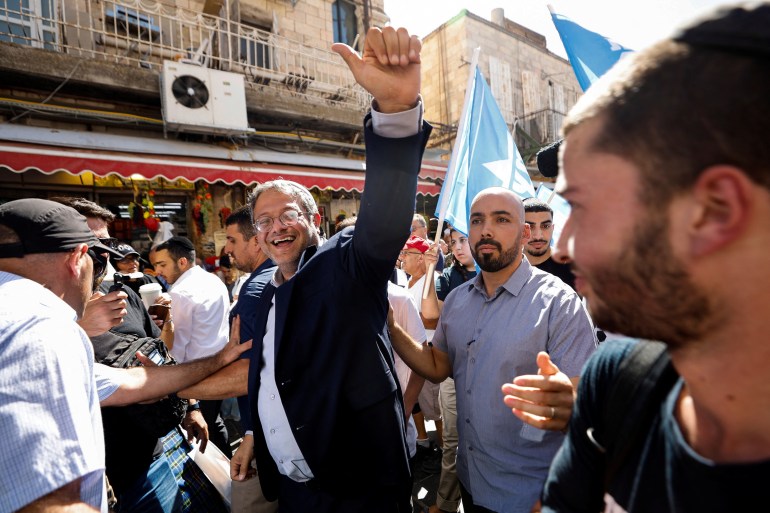Israeli far-right legislator Itamar Ben-Gvir, surrounded by security, waves at supporters on a walk around a Jerusalem market.