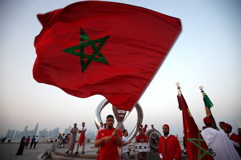 Des supporters marocains agitent un grand drapeau devant le compte à rebours de la Coupe du monde à Doha, au Qatar.