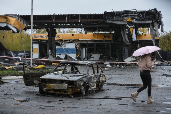 A woman passes by a gas station destroyed by Russian military strike