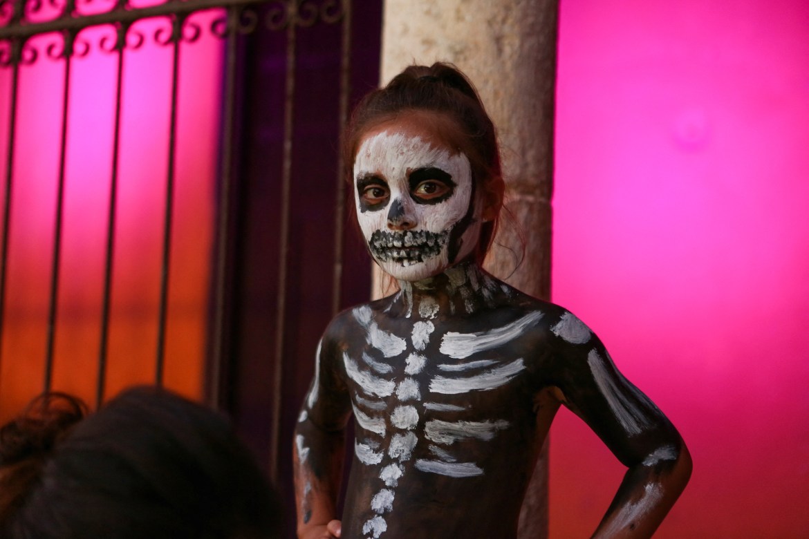 A boy with his body painted to resemble a skeleton