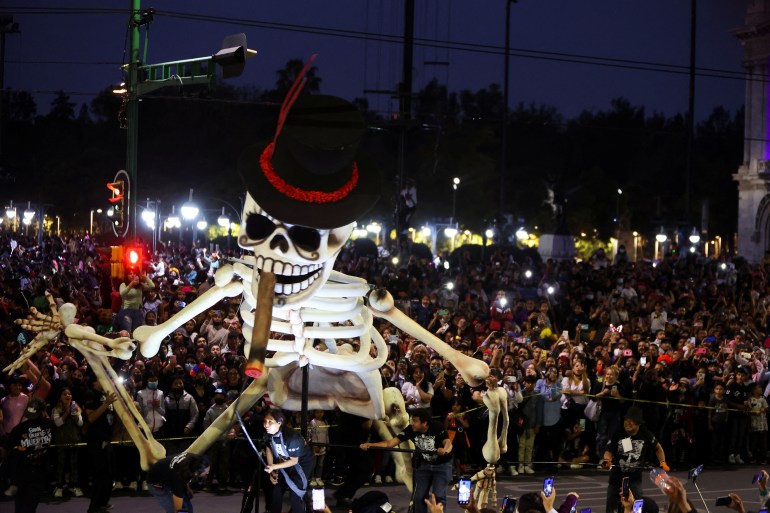 People look at a giant skeleton during the Day of the Dead parade, in Mexico City, Mexico October 29, 2022. REUTERS/Luis Cortes