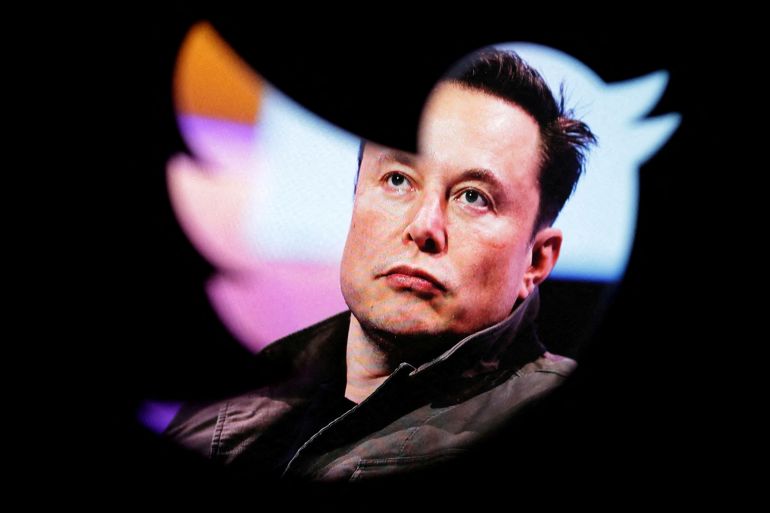 A photo of Elon Musk is seen through the cutout of a Twitter logo.
