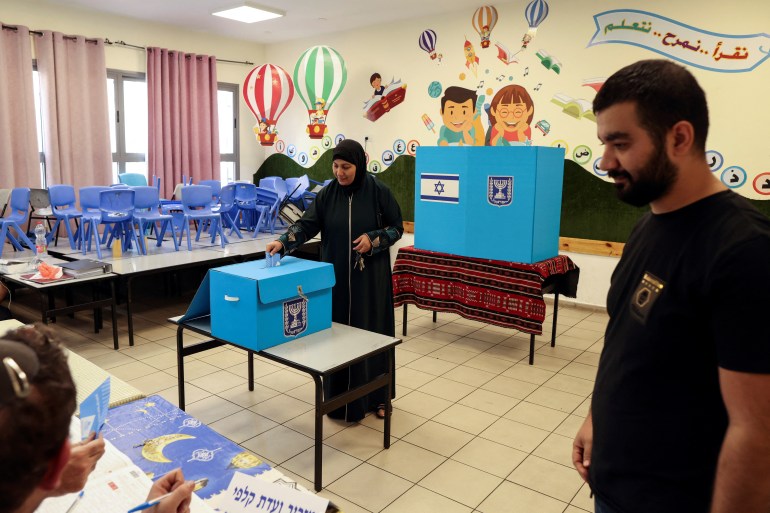 Uma mulher palestina israelense vota em uma sala de aula que foi transformada em uma estação de votação.