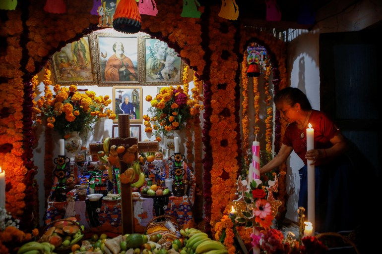A woman places a candle at an altar for her mother who died recently during the annual Day of the Dead celebration in Santa Fe