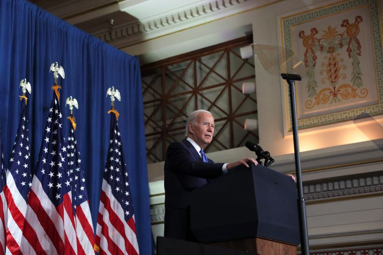 US President Joe Biden speaking at a podium with US flags