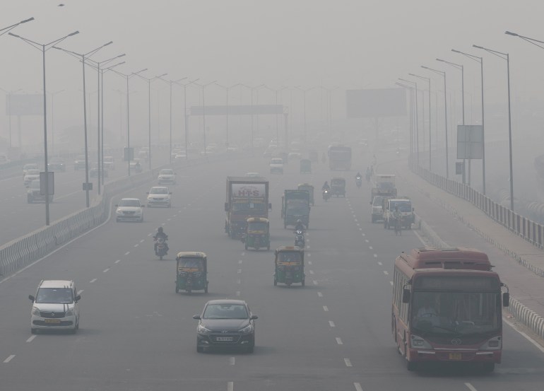 Véhicules sur une route de Delhi à peine visible à travers le smog