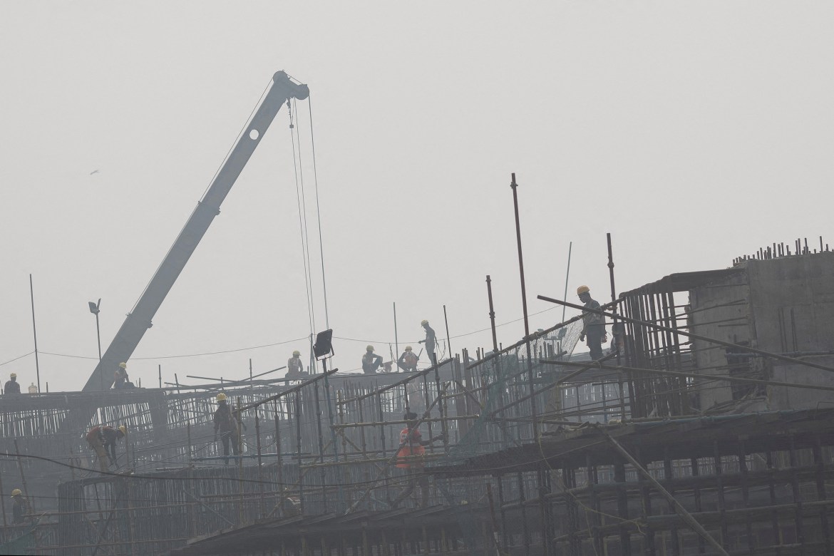 Labourers work at a construction site of a flyover.