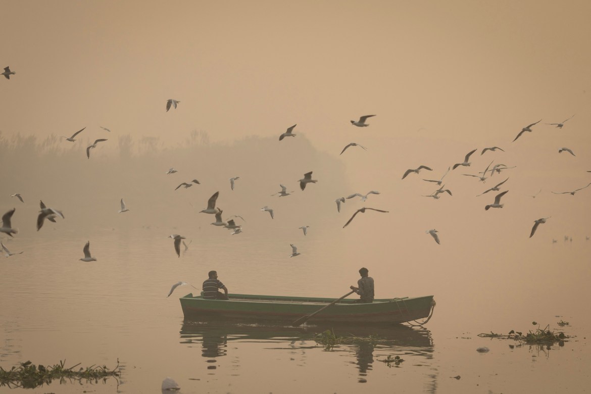 A man rows his boat in the Yamuna river amidst heavy smog.