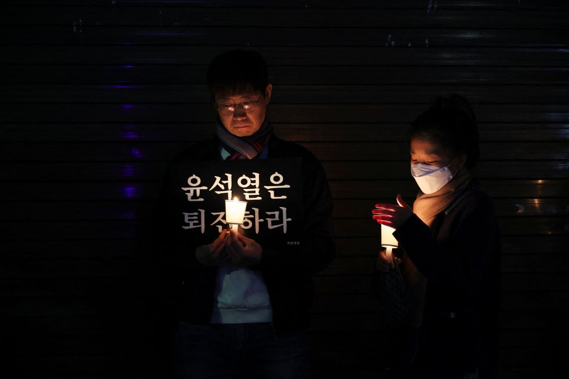 A man holds a placard during a candlelight vigil to commemorate the victims of the crowd crush that happened during Halloween festivities.