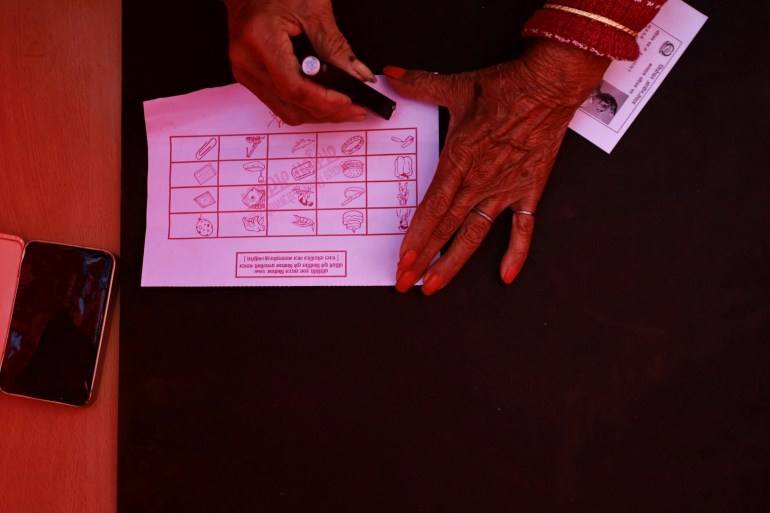A woman casts a vote during a mock election, held to familiarize people with the electoral process ahead of the general elections, in Lalitpur, Nepal