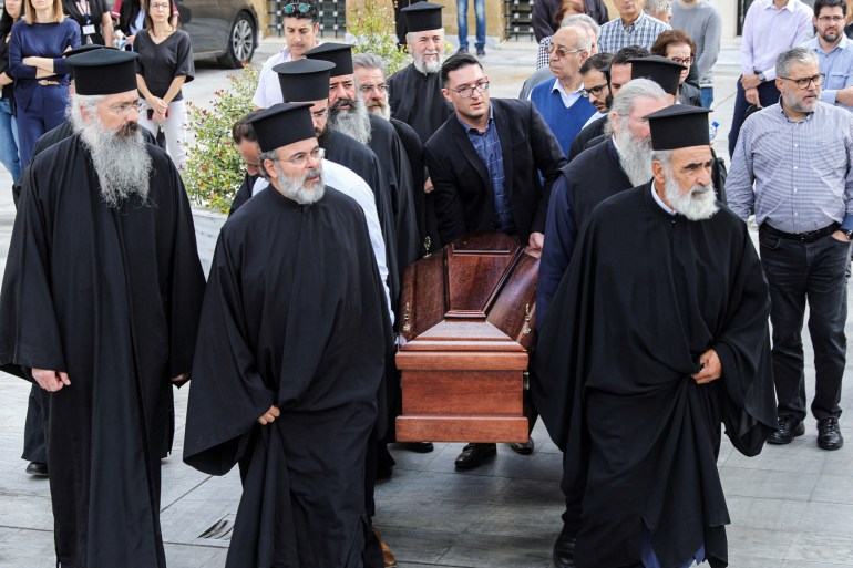 Greek Orthodox priests carry the coffin of the late Archbishop Chrysostomos II outside the Holy Archbishopric in Nicosia, Cyprus