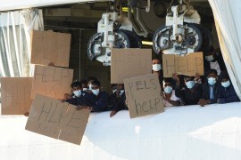 Migrants remaining on the rescue ship Geo Barents hold banners after Italy allowed the disembarkation of children and sick people.