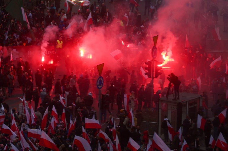 People carry Polish flags and flares during a march to mark the 104th anniversary of Polish independence in Warsaw