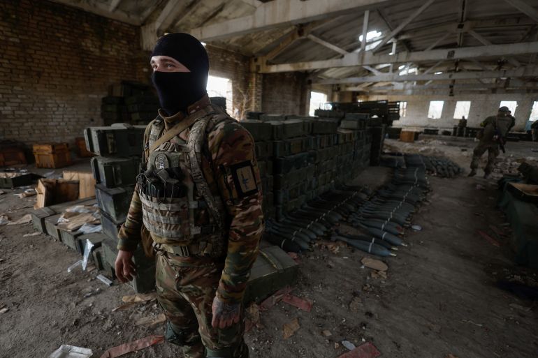 A Ukrainian soldier stands next to captured Russian ammunition in the village of Blahodatne