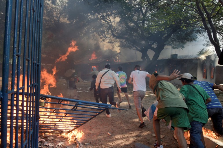 Protesters in Santa Cruz, Bolivia run past a burning gate
