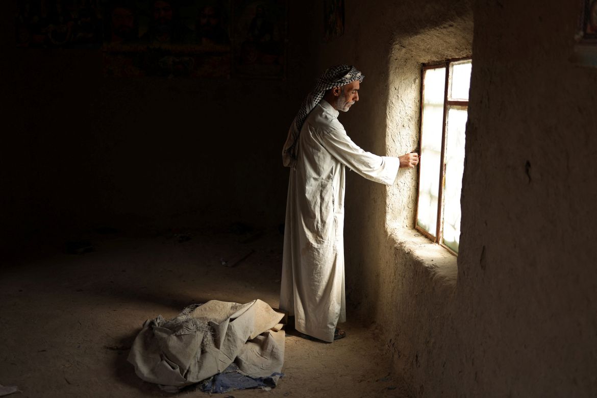 Taha Yassin, 46, stands inside the deserted home of his neighbour.