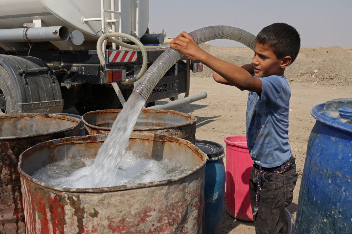 Haider Jalil, 10, fills a water tank from a truck outside his family home