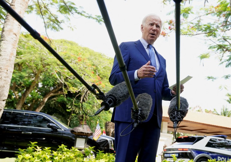 US President Joe Biden is seen through a microphone with a long handle speaking to the media in Bali
