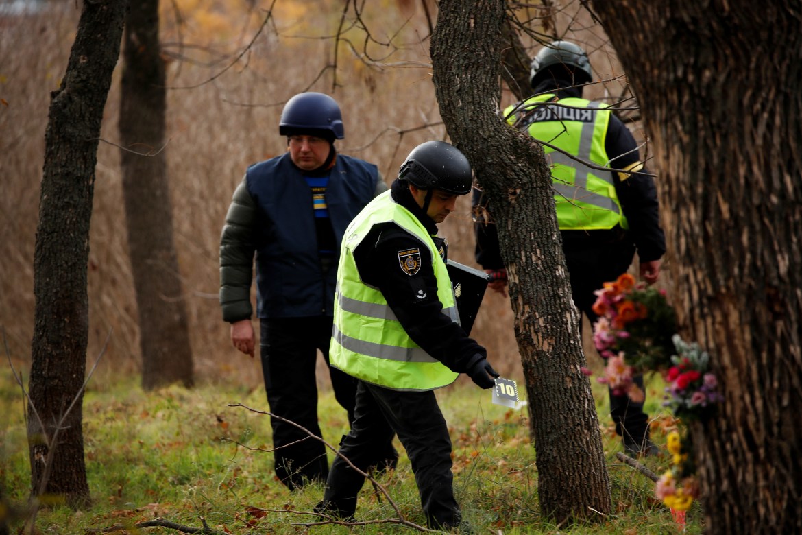 Ukrainian police forensic experts search for evidence at a park where fighting took place