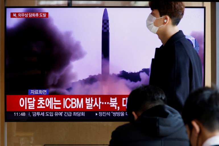 a man walks past a giant TV screen showing a missile launch. The strap shows ICBM