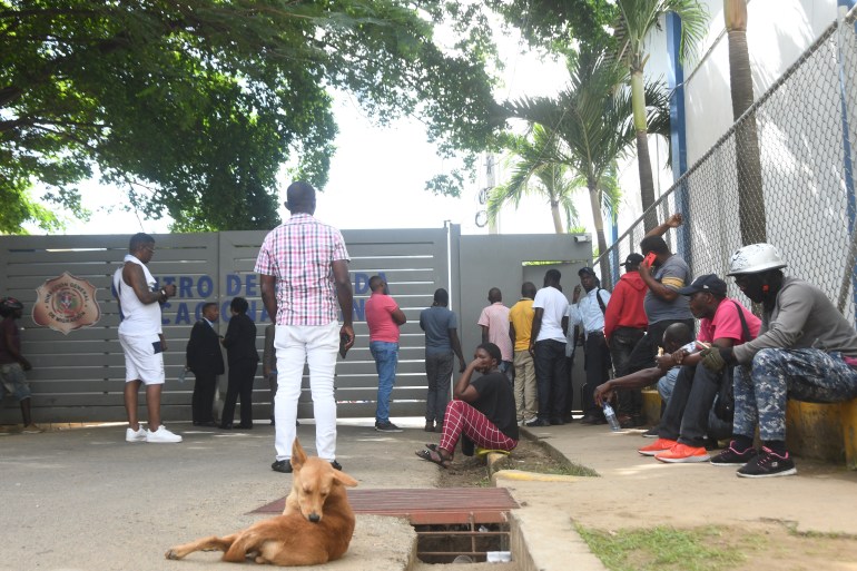 People stand outside a migration clearance centre in Santo Domingo