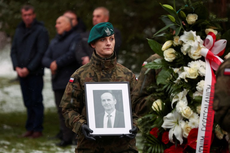 A military member carries a picture of one of two victims of a missile that hit a southeastern Polish village near the border with Ukraine, during his funeral in Przewodow, Poland November 19, 2022.