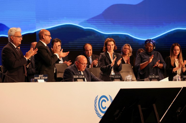 Delegates applaud as COP27 President Sameh Shoukry delivers a statement during the closing plenary at the COP27 climate summit in Red Sea resort of Sharm el-Sheikh