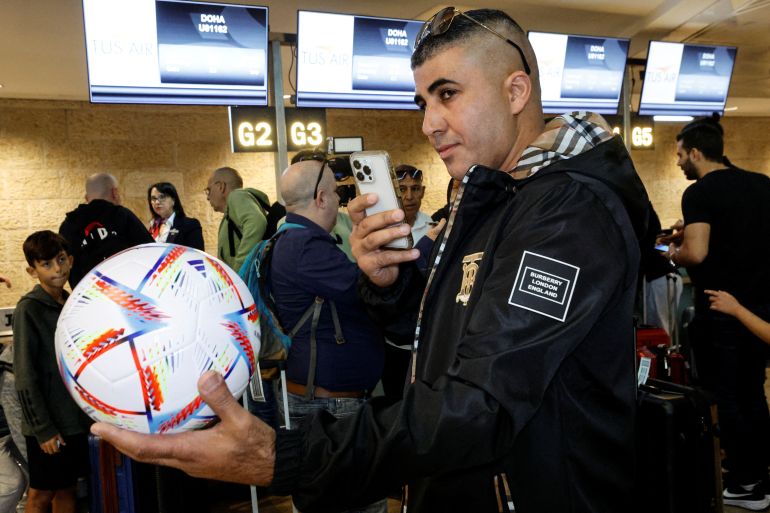 A football fan takes a photograph of a football, before boarding the first direct commercial flight between Israel and Qatar for the upcoming 2022 FIFA World Cup Qatar, at Ben Gurion International Airport, near Tel Aviv, Israel November 20, 2022. REUTERS/Amir Cohen