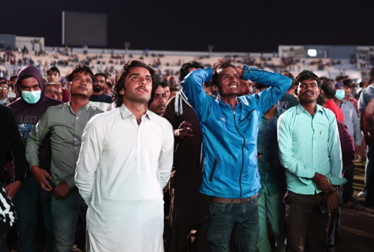 Migrant workers watch the match between Qatar and Ecuador on a video screen in Doha, Qatar.