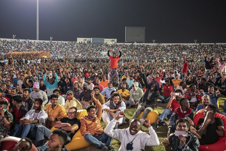Migrant workers watch the Qatar v Ecuador match on video screens in Doha, Qatar.