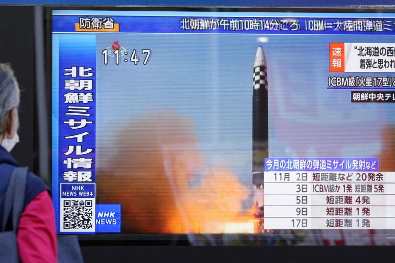 A passerby looks at a television screen showing a report about North Korea missile launch