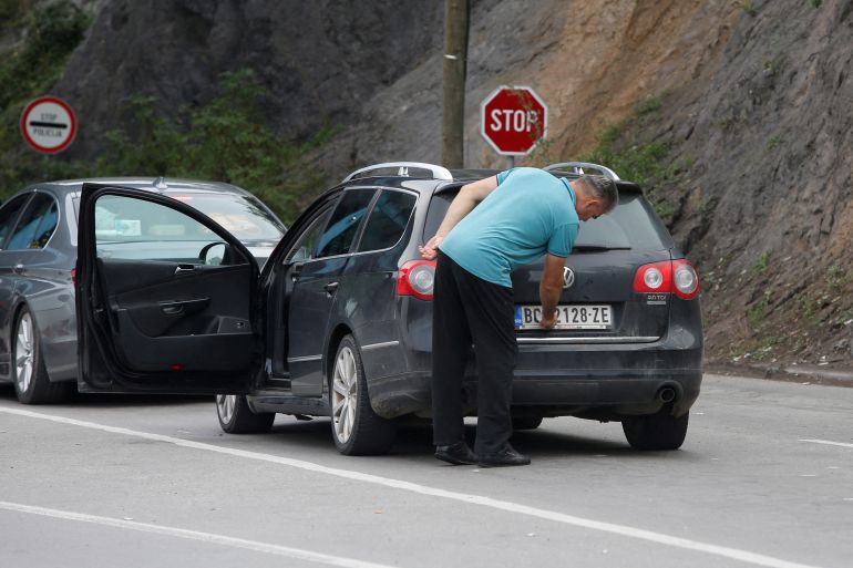 A driver removes a sticker covering the national markings on his car plates at the Jarinje border crossing, Kosovo.