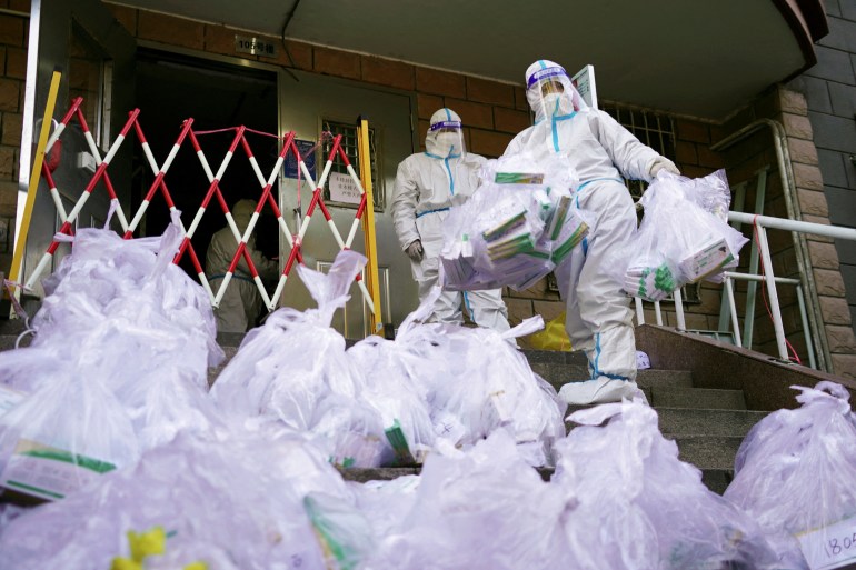 Workers in protective suits prepare to enter a building under lockdown to distribute to residents antigen testing kits for the coronavirus disease (COVID-19), at a residential compound in Beijing's Chaoyang district, China November 21, 2022. China Daily via REUTERS ATTENTION EDITORS - THIS IMAGE WAS PROVIDED BY A THIRD PARTY. CHINA OUT.
