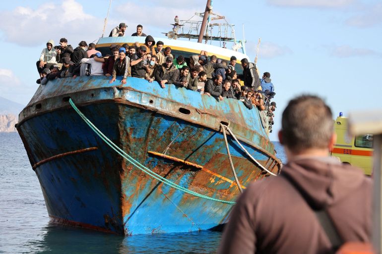 Migrants stand onboard a fishing boat at the port of Paleochora